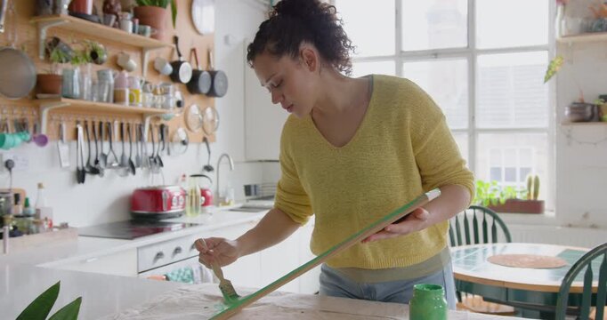 Young Woman Painting a shelf in her cosy Kitchen