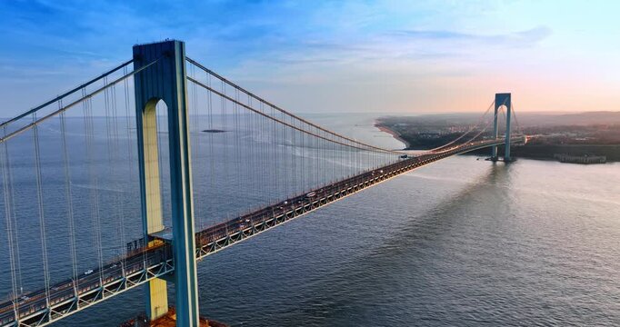 Flying towards the Verrazzano-Narrows Bridge over the vast waterscape. Many cars move by the structure.