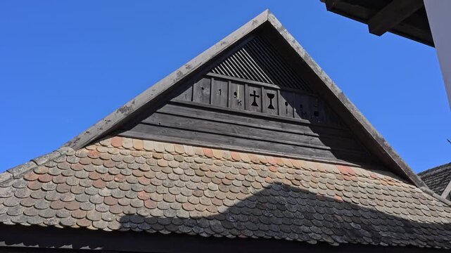 Historic Tiled Roof with Carved Wooden Gable and Religious Symbols