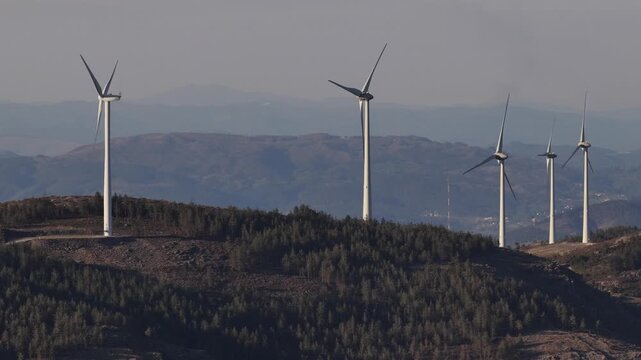 Aerial view of sleek wind turbines standing tall against the backdrop of rolling hills, a testament to sustainable energy, Amarante, Portugal.