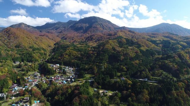 紅葉の秋山郷の小赤沢集落と槍ノ塔と苗場山などの山並み