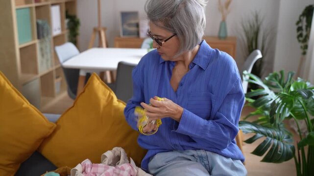 Mature woman seamstress rolling up measuring tape