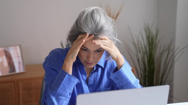 Stressed mature businesswoman suffering from headache at work