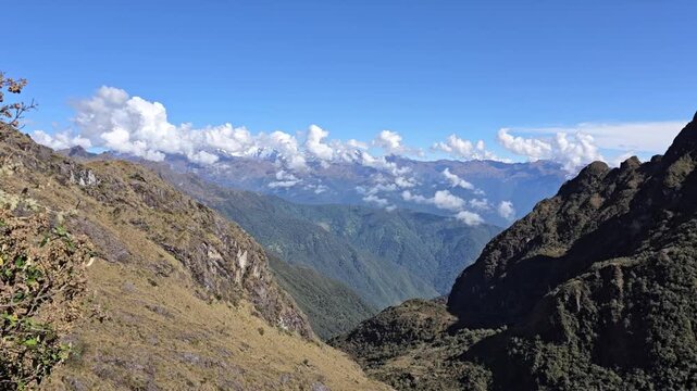 Cusco Region, Peru - 25 June 2024. Panoramic view over deep valley with steep mountain ridges and drifting clouds under clear sky on the Inca Trail.