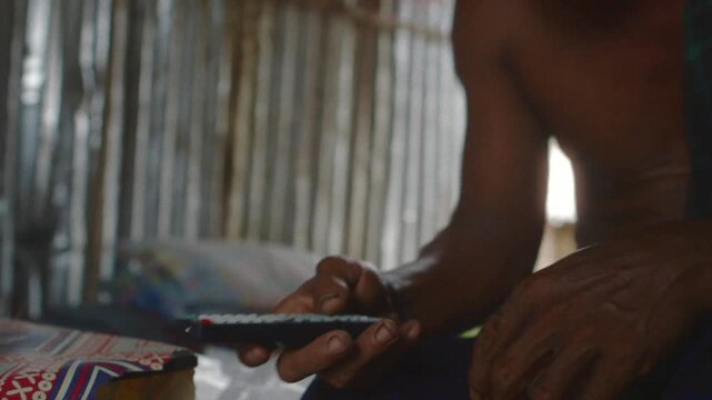 Burmese man relaxing at home while using a remote control to turn on a device