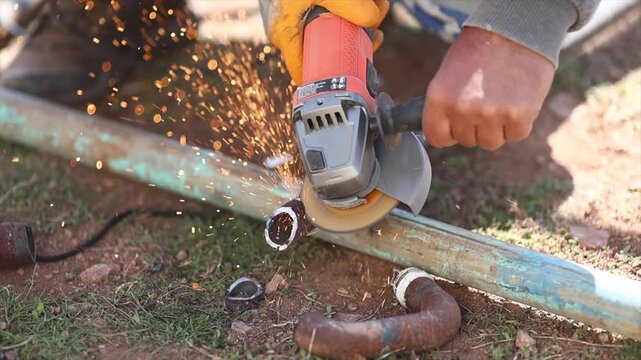Man is cutting a metal list by angle grinder saw.
