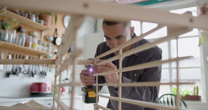 Young Adult Male Assembling a piece of flat pack furniture at home