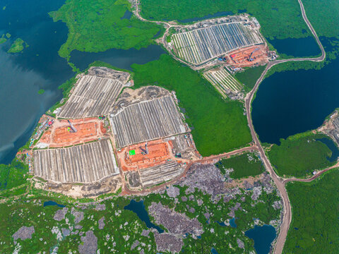 Aerial view of geometric patterns of aquaculture farms contrasting with the surrounding green vegetation and dark water bodies, Dhaka, Dhaka Division, Bangladesh.