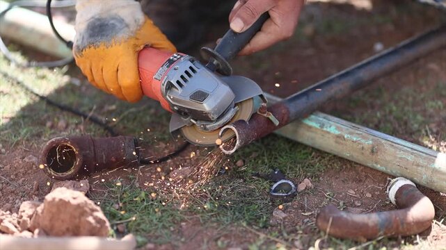 Man is cutting a metal list by angle grinder saw.