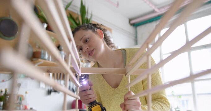 Young Adult Woman Assembling a piece of flat pack furniture at home