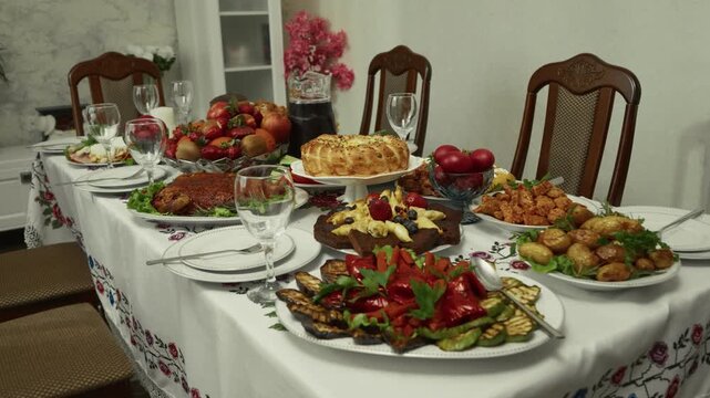 Festive dining table set with various traditional dishes, fruits, and drinks, showcasing a vibrant spread in a cozy indoor setting with decorative elements