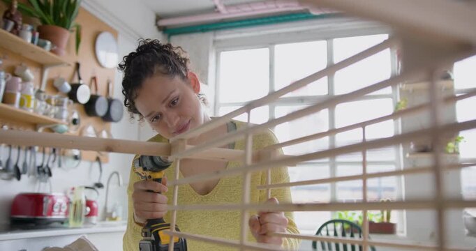 Young Adult Woman Assembling a piece of flat pack furniture at home