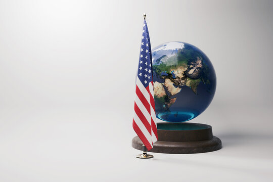 American flag standing next to a realistic earth globe on a wooden base. Symbol of US global influence, international relations, and geopolitics. Studio shot on a clean white background
