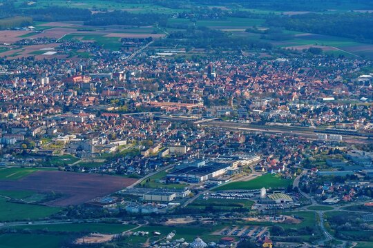 Aerial view of a sprawling cityscape nestled amid patchwork fields and verdant forests, a symphony of urban and rural textures, Kintzheim, Grand Est, France.