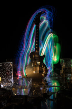 Music Concept: Guitar Miniature on a Dark Background with Vivid Light, Smoke, and Fire Effects. Golden electro guitar under a Dramatic Spotlight.