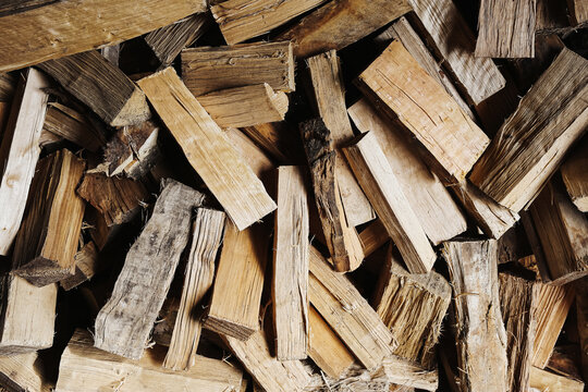 Stack of chopped firewood pieces. Wooden logs texture background. Natural fuel material for heating concept. Rustic timber pile with rough cut surfaces and organic pattern.