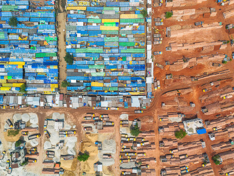 Aerial view of a striking contrast between the blue and green buildings juxtaposed against the earthy tones of brick piles, Dhaka, Dhaka Division, Bangladesh.