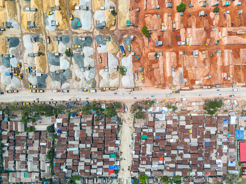 Aerial view of contrasting textures of raw materials, vibrant red soil, and clustered rooftops create a compelling tapestry, Dhaka, Dhaka Division, Bangladesh.