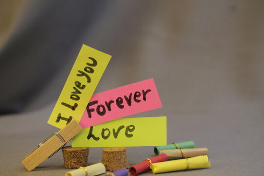 Mensajes de amor y amistad sostenido con un gancho de Madera y fondo desenfocado.