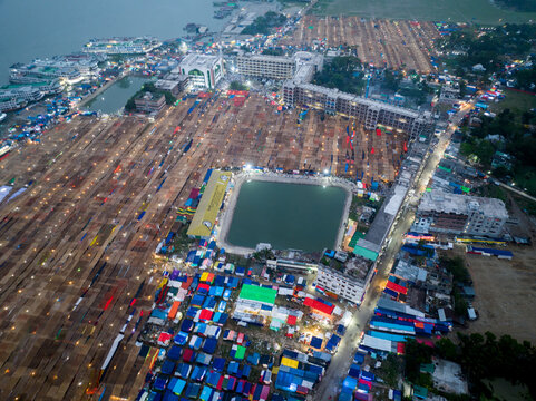 Aerial view of a sprawling landscape dotted with colorful tents and buildings converging around a serene pond, Charmonai, Barisal Division, Bangladesh.