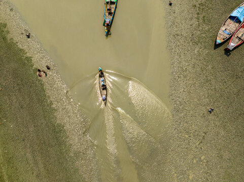 Aerial view of boats sailing on the tranquil river, their wakes creating mesmerizing patterns on the water's surface, Charmonai, Barisal Division, Bangladesh.