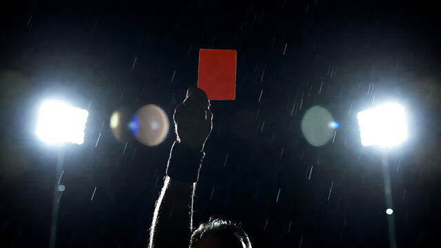 Referee showing red card at football stadium, decision for foul play, disqualification during sports event, soccer match penalty