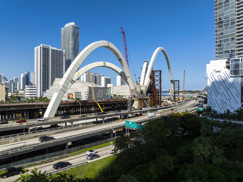 Aerial view of the vibrant cityscape where the new Signature Bridge's gleaming white arches contrast against the towering skyscrapers, Miami, Florida, USA.