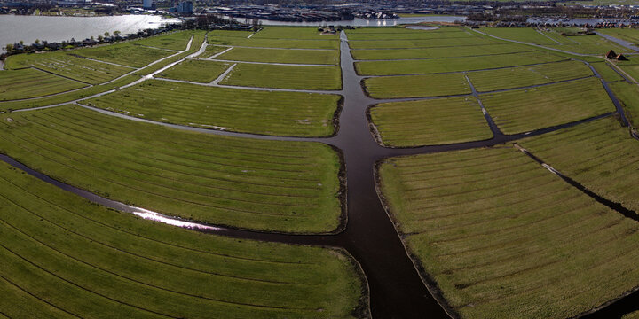 Aerial view of emerald green fields intersected by dark waterways create a striking contrast in the Schaalsmeerpolder, Wormer, Netherlands.