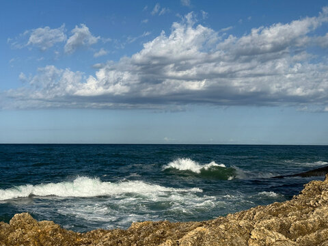 Stormy sea waves roll onto the rocky coast.
