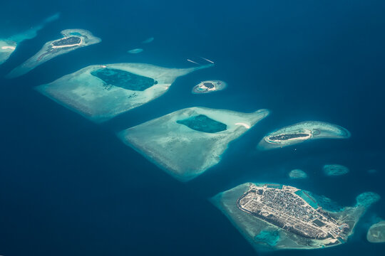 Aerial view of the islands scattered like emerald jewels amidst the sapphire sea, a tropical paradise unfolds from above, Flight from Male to Hanimaadhoo island, Maldives.