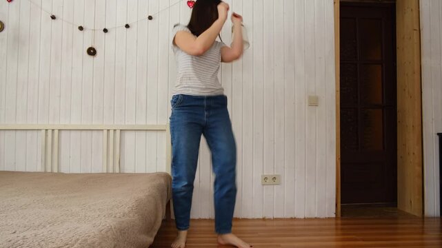 Relaxed woman enjoying by dining room. Casual morning cheerful woman dancing. Girl in bright kitchen singing playful stretches. Young adult female twirls, grooves. Lady moves to music, feels overjoyed