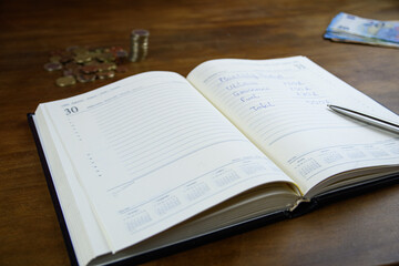 Fototapeta premium Expense notes in planner with coins and cash