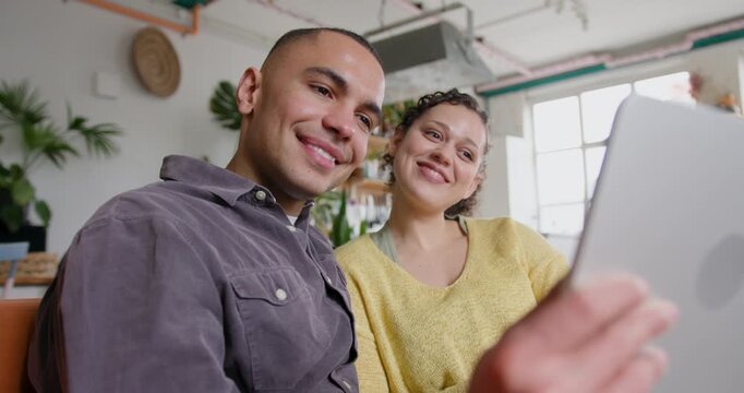 Young Couple Streaming entertainment on their Digital tablet on Sofa at Home