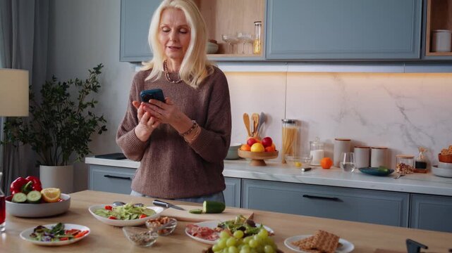 Mature blonde woman answers phone call as cooks dinner in kitchen