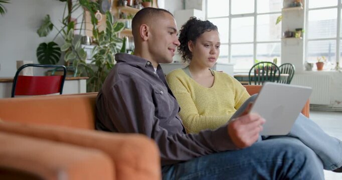 Young Couple Streaming entertainment on their Digital tablet on Sofa at Home