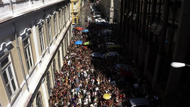 Aerial view, Drone Footage of crowded people partying in carnival block Parade in downtown Rio de Janeiro Pra&ccedil;a XV with old and modern buildings in background in sunny day