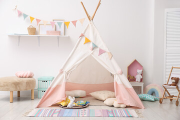 Cute wigwam with pillows, books and toys in stylish child's room © New Africa