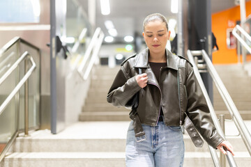 Fototapeta premium Girl in black leather jacket walks down the stairs to a metro station