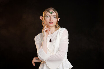 Naklejka premium Beautiful girl dressed as elf on black background with smoke
