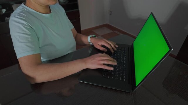 Woman Typing on Laptop with Green Screen for Easy Content Integration