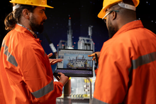 Offshore platform crew staff members checking equipment status indicators on laptop system dashboard. Coworkers doing brainstorming, using notebook digital monitoring panel