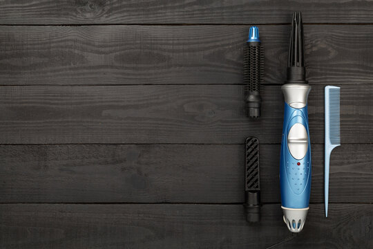 Hair styler with care products on wooden background, top view