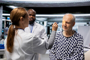 Doctor and nurse in a clinical trial institute examining a patient, studying the effects of a new...