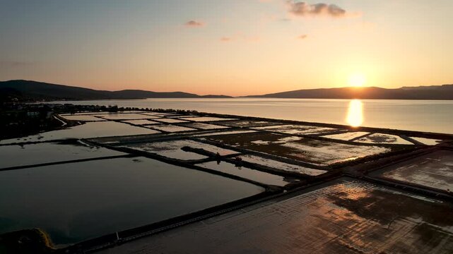 4K aerial drone footage over the salt pans of Polichnitos, Lesvos island, Greece, iduring golden hour, revealing geometric patterns and warm Mediterranean light in a serene coastal landscape.