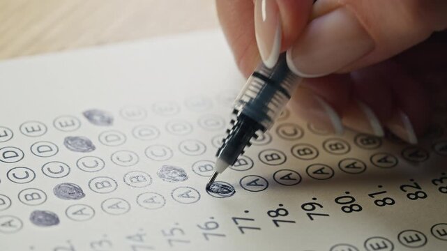 Close-up footage of a student completing a test and marking answers on paper. Concept of exams, education, knowledge testing, certification and academic achievement.