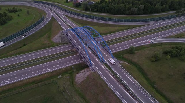Top-down drone view of highway overpass crossing multilane roadway. Geometric transport scene with modern infrastructure design.