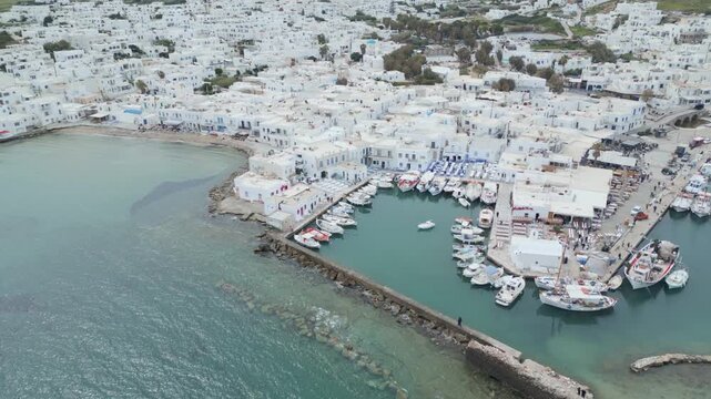 Aerial drone view of Naousa village on Paros island, Greece, showing traditional white buildings, coastal harbor and clear blue sea in daylight. Ideal for travel, tourism and Mediterranean lifestyle 