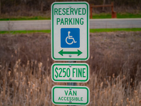 Reserved accessible parking sign with wheelchair symbol and $250 fine notice indicating van accessible space in public lot