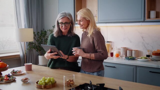 Old woman shows grandkids photos on digital tablet to friend