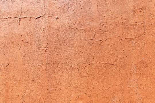 Orange textured wall with peeling paint. Terracotta colored stucco wall background